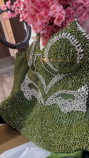 Close-up of a green beaded bodice with silver embellishment